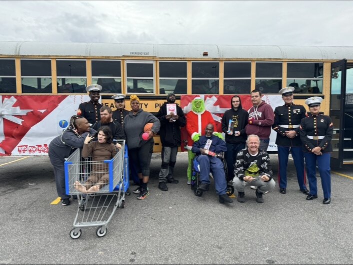 Community members and Marines gathered in front of the Stuff the Bus school bus