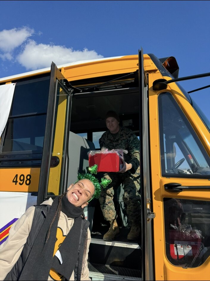 A Marine handing down a donated gift from a school bus